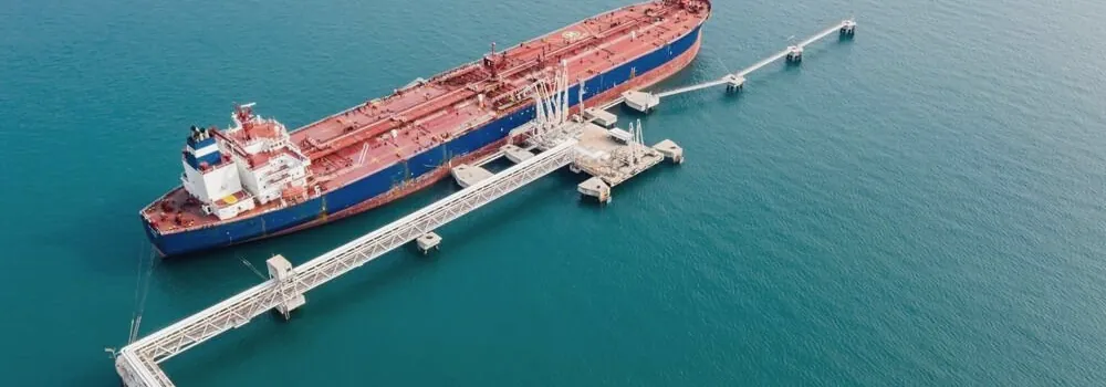 Product carrier alongside a terminal berth, connected to the jetty loading platform